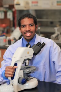 Former student, current doctor posing with microscope