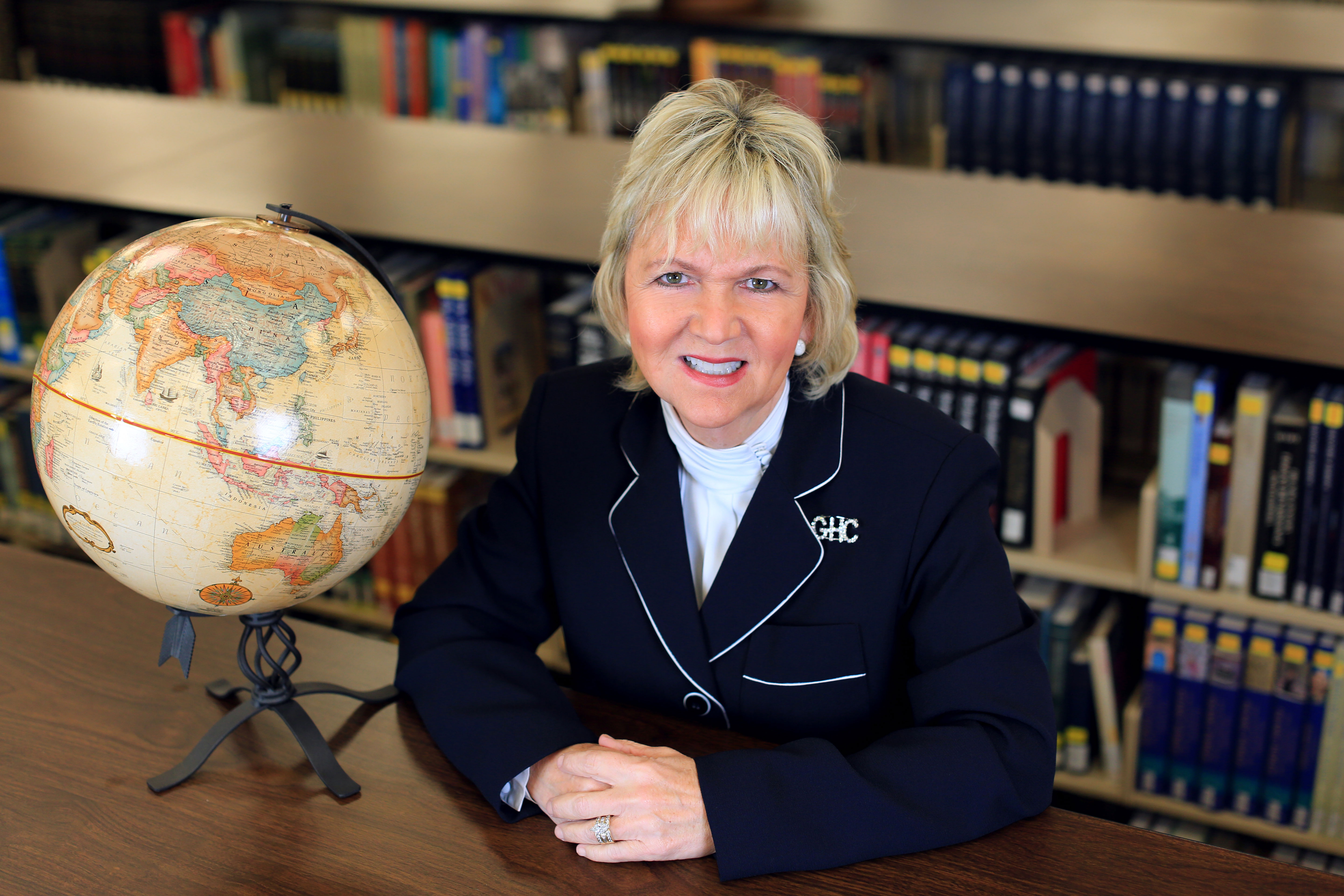 teacher behind desk beside globe