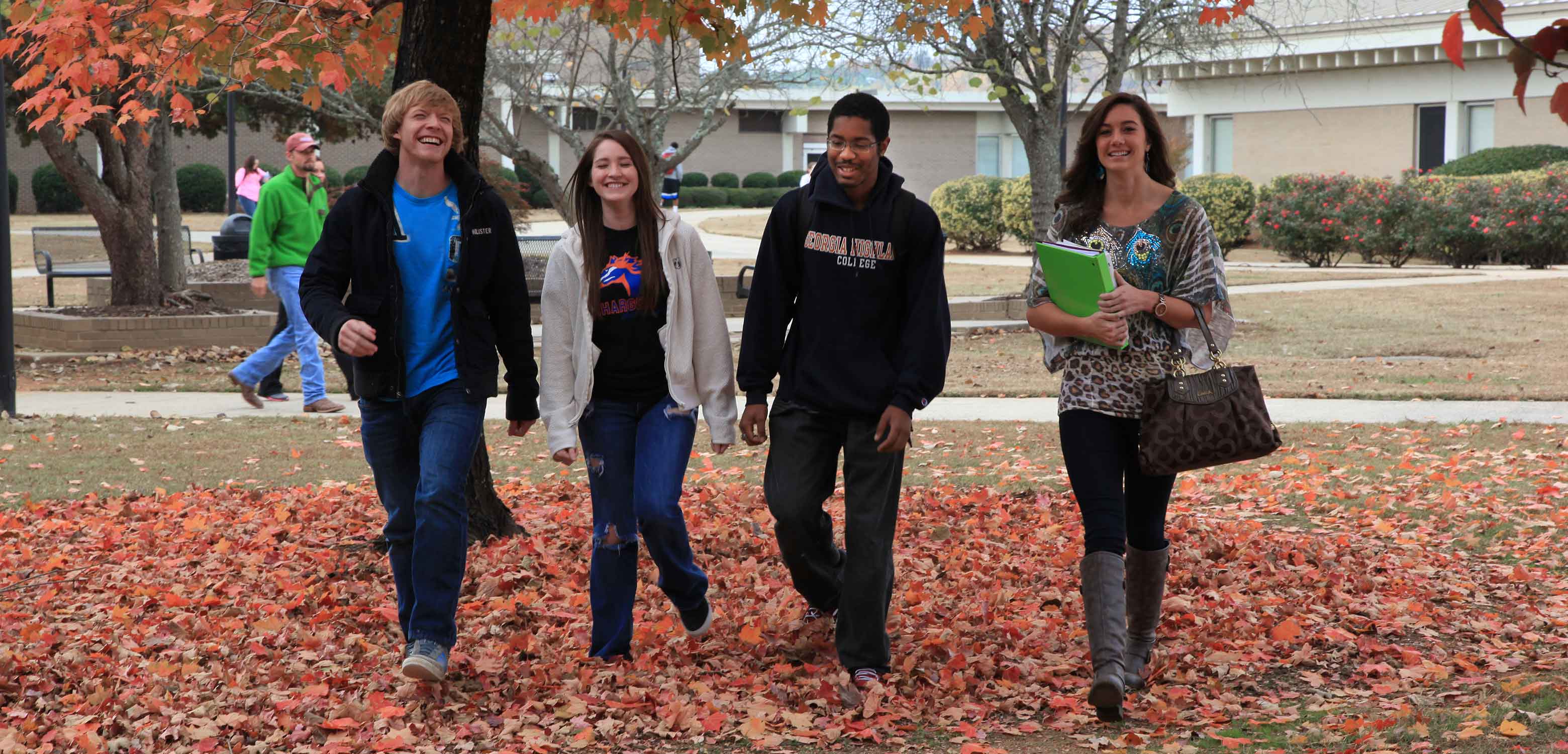 four students walking in the leaves