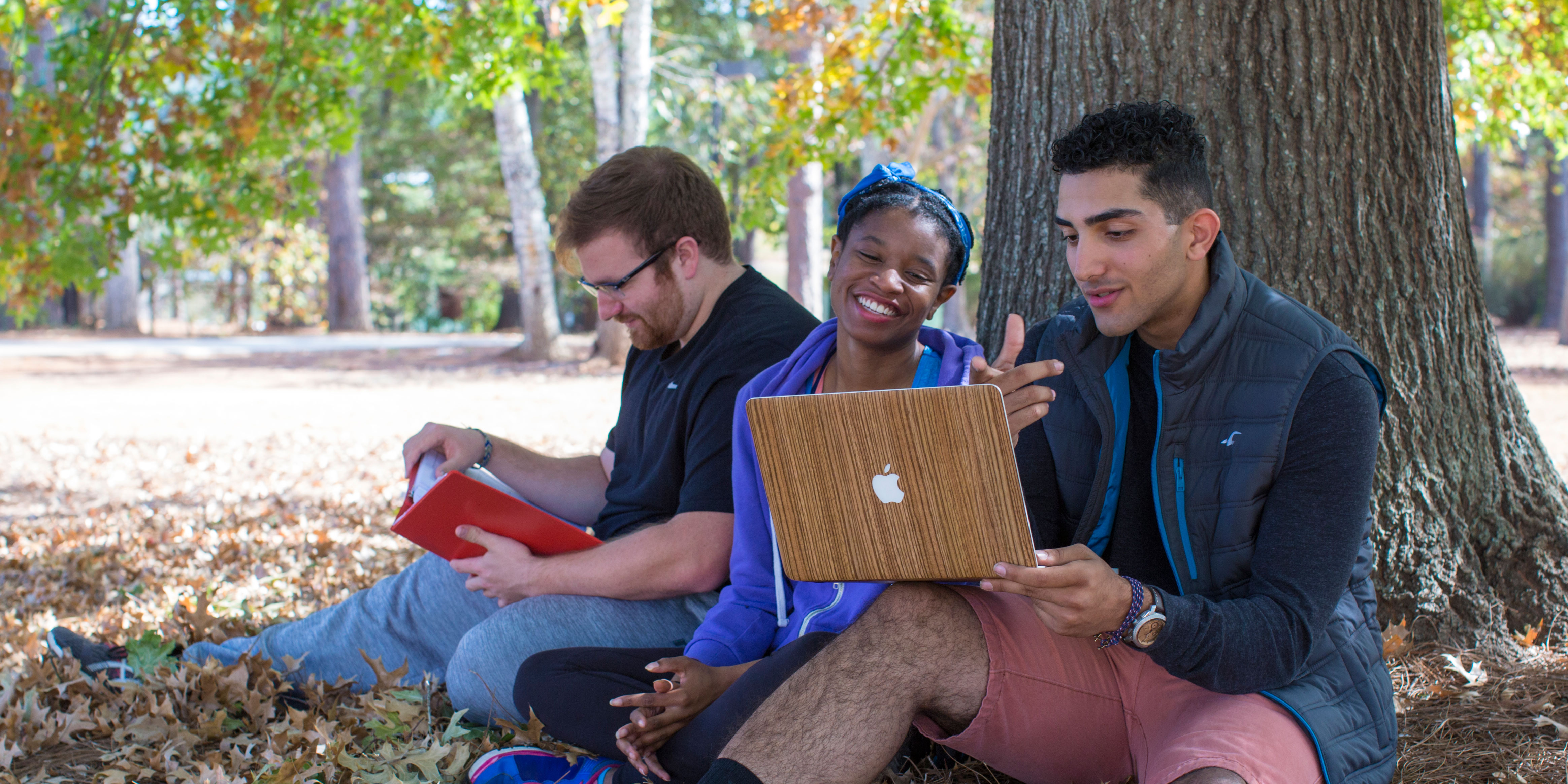 GHC students sitting around laptop under tree